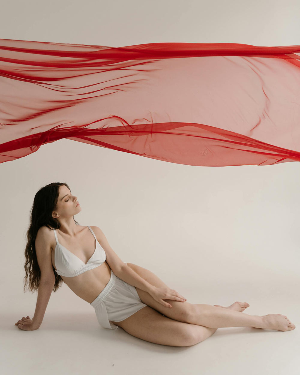 Une femme en petite tenue sous un tissu rouge